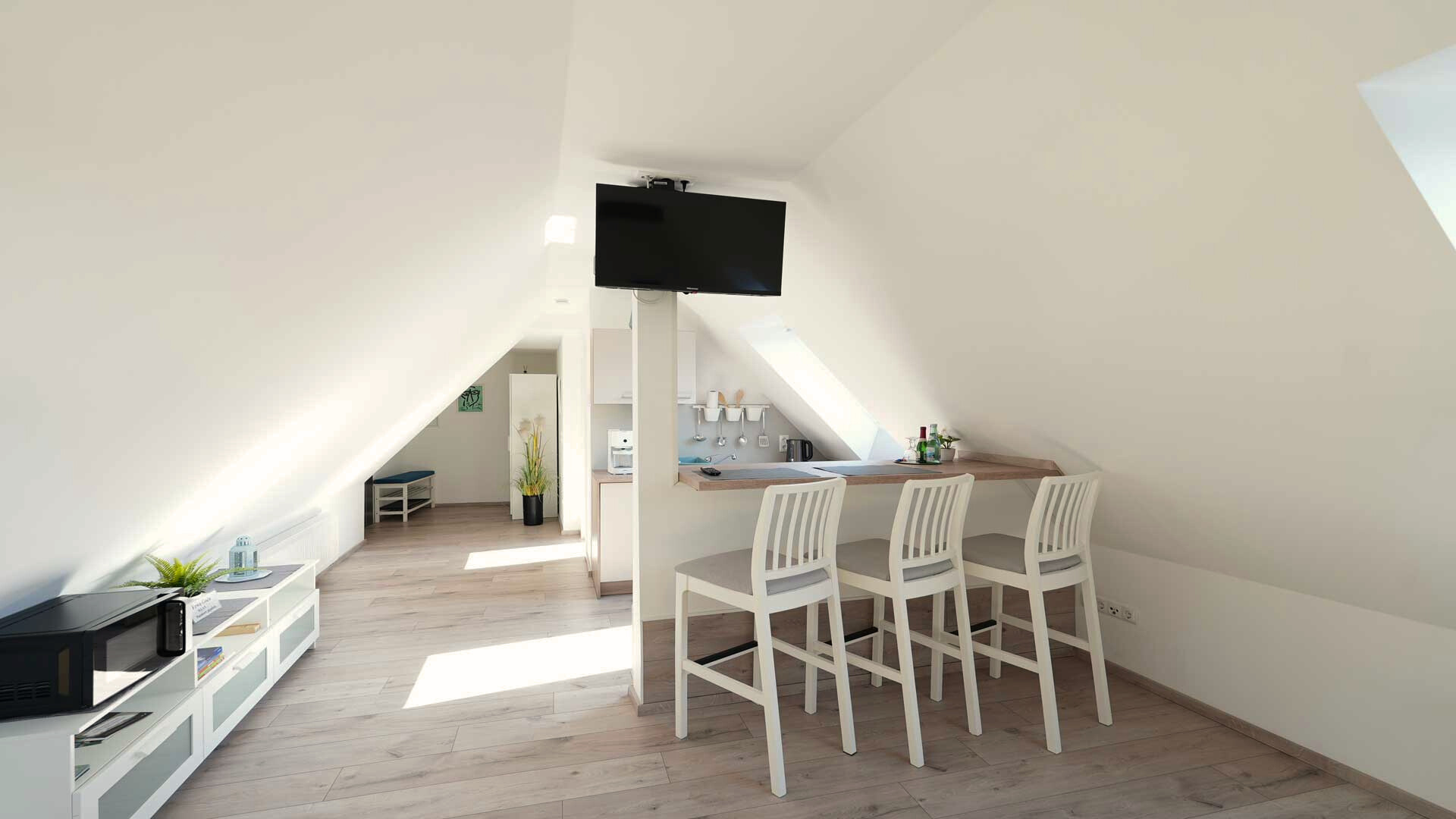 ferienwohnung-bad-koenigshofen-dachgeschoss-kueche-tv Helle Dachgeschoss-Ferienwohnung mit offener Küche, Bartresen und Flachbild-TV in Bad Königshofen.