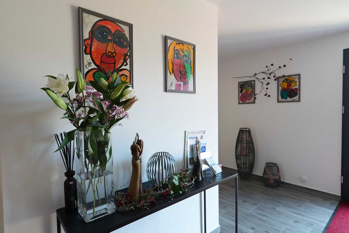 Dekorativer Eingangsbereich einer Ferienwohnung mit Kunst an der Wand, frischen Blumen und stilvollen Accessoires.