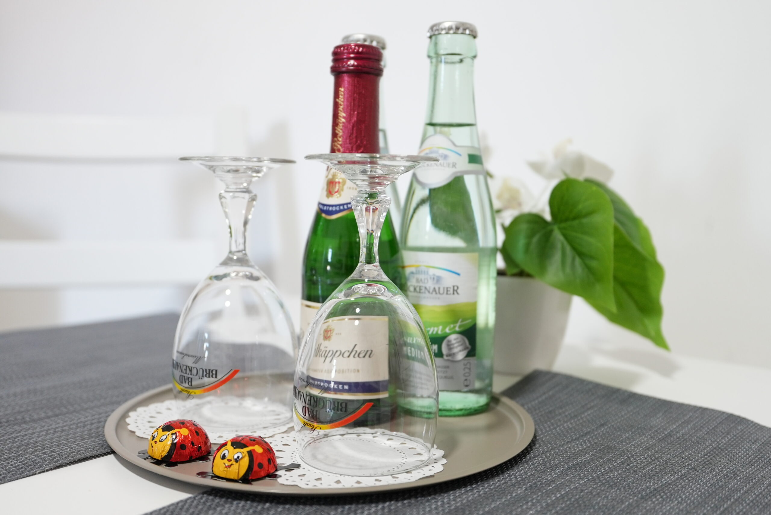 Begrüßungstablett mit Sekt, Mineralwasser und Gläsern auf rotem Tischläufer